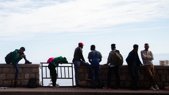 Geflüchtete warten an der Grenze zwischen Italien und Frankreich in Ventimigila an einer Mauer. © picture alliance / AA | Ibrahim Ezzat 
