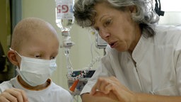 Ein leukämiekranker Junge spielt auf der Krebsstation mit einer Pädagogin. © picture-alliance/dpa 