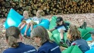 Kinder und ProducerInnen sitzen im Wald und haben Textblätter auf dem Schoß. © NDR Foto: Anna Bohaumilitzky