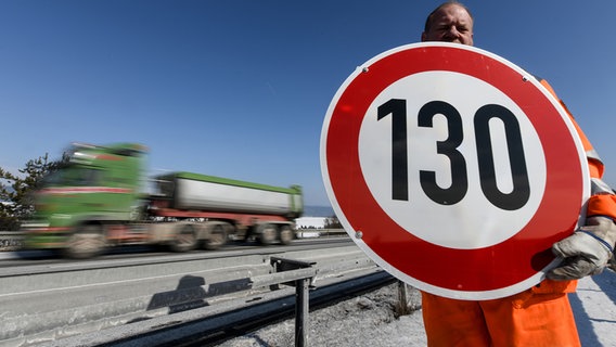 Ein Straßenwärter hält an der Autobahn A81 am Hegaublick ein Schild mit der Aufschrift "130" in den Händen. © picture alliance Foto: Patrick Seeger