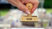 Auf einem Holzstempel steht Visum © picture alliance / Bildagentur-online/McPhoto | Bildagentur-online/McPhoto 