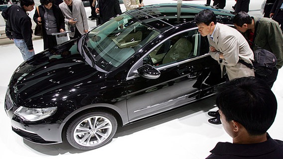 Besucher sehen sich auf der Autoschau in Peking ein Volkswagenmodell an © ap Foto: Greg Baker