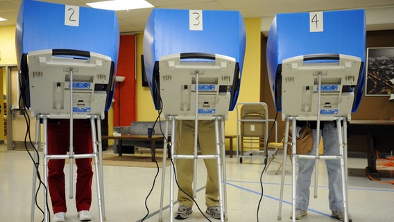 Drei Menschen stehen hinter Wahlautomaten bei der Wahl in Allentown, Pennsylvania, USA, 2010.  