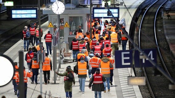 Streikende Mitglieder der EVG tragen Fahnen und Streikwesten und gehen über einen Bahnsteig im Hamburger Hauptbahnhof. © dpa-Bildfunk Foto: Bodo Marks
