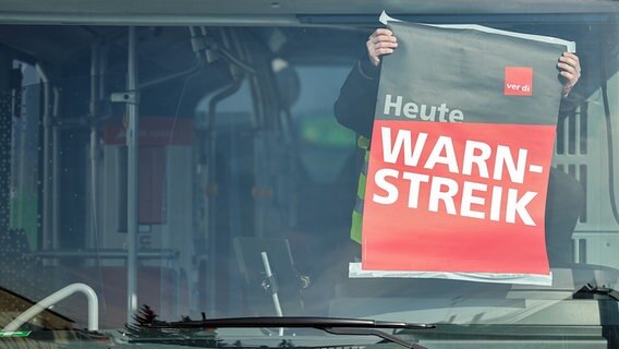 Ein Mitarbeiter eines Busunternehmens befestigt ein Warnstreik-Plakat während eines Warnstreiks in einem Bus auf einem Betriebshof. © dpa bildfunk Foto: Jan Woitas