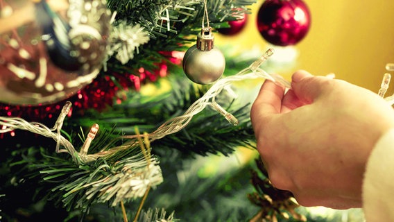 Jemand schmückt einen Weihnachtsbaum © imago images/Cavan Images 