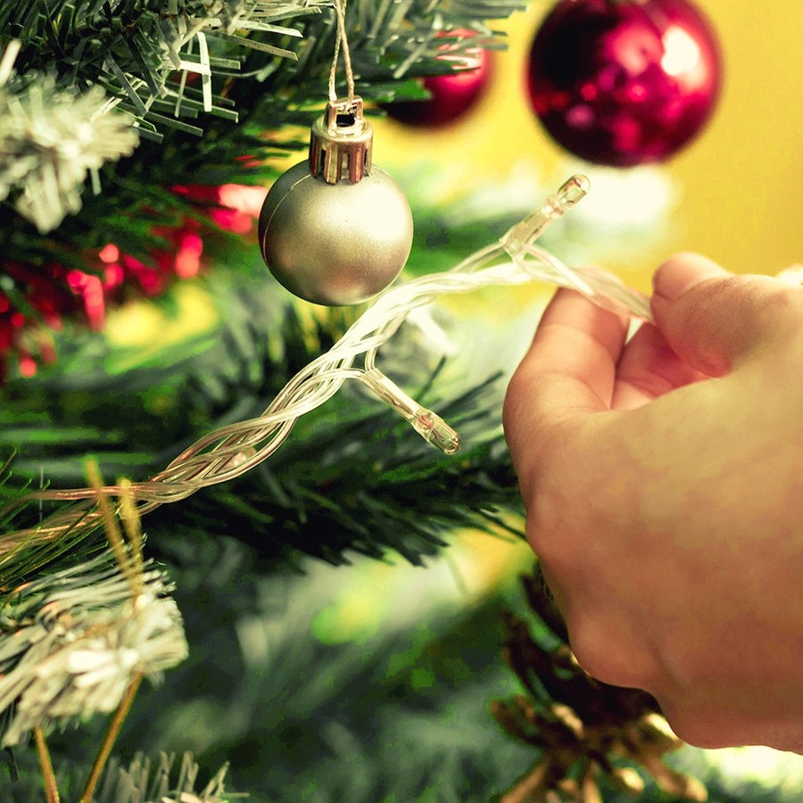 Jemand schmückt einen Weihnachtsbaum © imago images/Cavan Images 