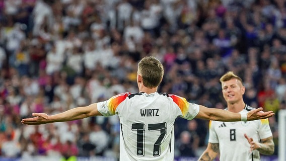 Der deutsche Fußball-Nationalspieler Florian Wirtz (l.) bejubelt sein Tor im EM-Eröffnungsspiel gegen Schottland. Toni Kroos läuft auf Wirtz zu, um ihm zu gratulieren. © Christian Charisius/dpa 
