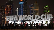 Fans machen vor dem Schriftzug "Fifa Worldcup Qatar 2022" in der Stadt Doha Fotos. © dpa bildfunk Foto: Federico Gambarini