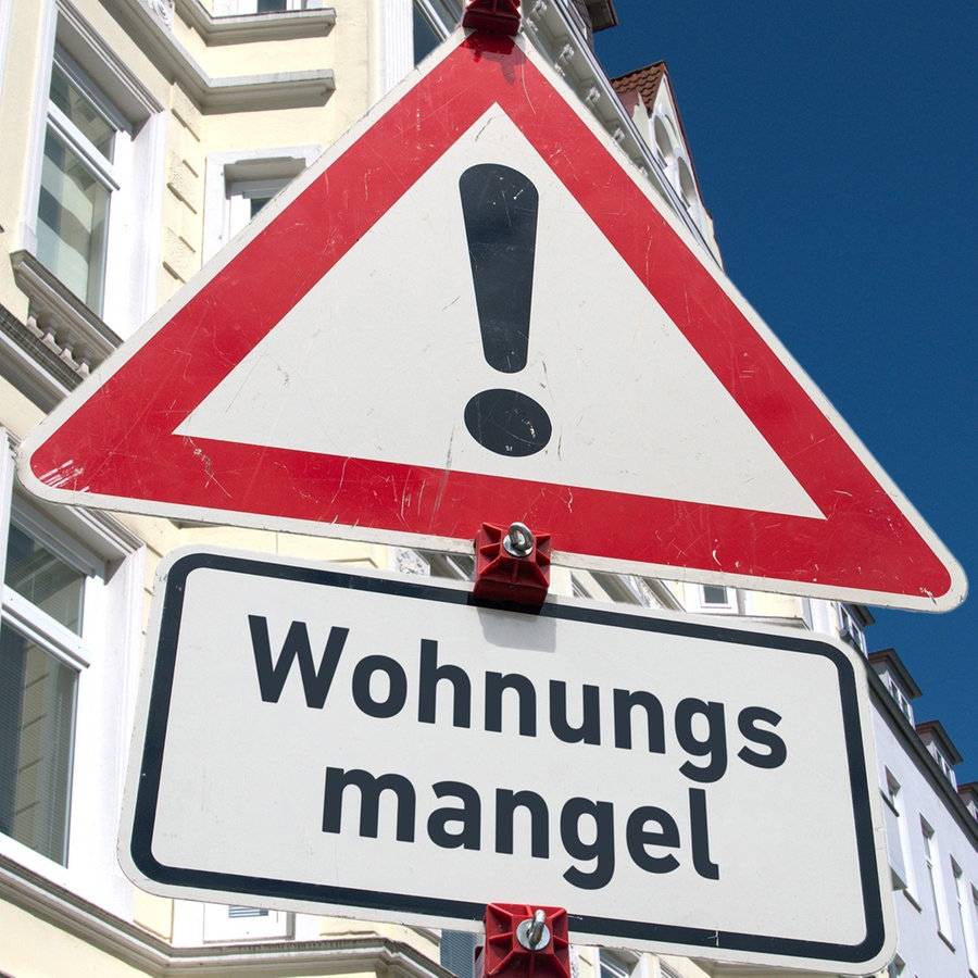 Ein Baustellenschild mit der Aufschrift "Wohnungsmangel" vor einer Hausfassade © picture alliance / SULUPRESS.DE Foto: Torsten Sukrow / SULUPRESS.DE