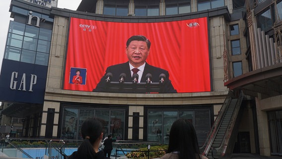 Auf einem großen Screen an einer Hauswand ist Xi Jinping bei einer Rede zu sehen. © picture alliance / DFoto 