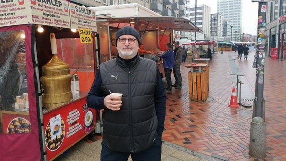DAVA-Gründungsmitglied Mustafa Yoldas steht in der Großen Bergstraße in Hamburg-Altona und hält ein türkisches Heißgetränk in der Hand. © NDR Info Foto: Marc-Oliver Rehrmann