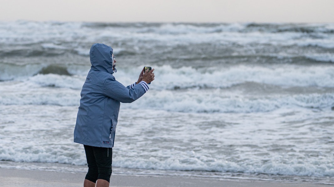 Eine Frau fotografiert das stürmische Meer