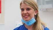 Kinga Ostrowski, gehörlose Zahnarzthelferin, mit einem herunter geklappten Mundschutz. © NDR Info Foto: Bettina Less