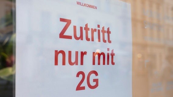 In einem Geschäft hängt ein Schild mit der Aufschrift "Zutritt nur mit 2G". © dpa Foto: Christophe Gateau