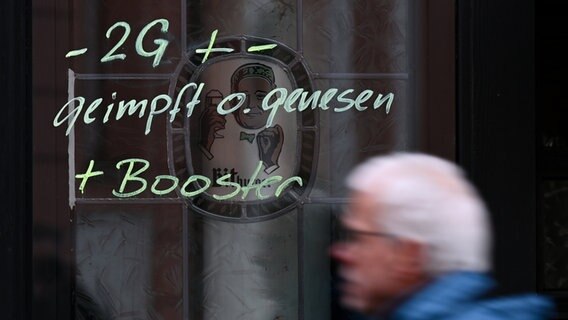 Am Fenster einer Kneipe ist der Hinweis "2G + - geimpft o. genesen + Booster" aufgemalt. © dpa Foto: Arne Dedert