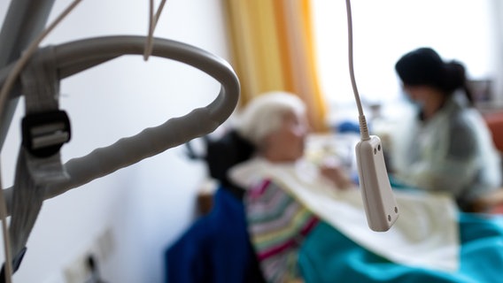 Eine Altenpflegerin reicht einer Bewohnerin auf einer Pflegestation das Essen an. © picture alliance Foto: Sven Hoppe
