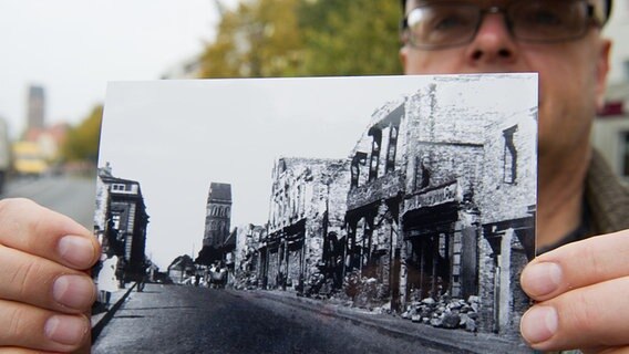Der Mitarbeiter des städtischen Museums in Anklam, Peer Wittig, zeigt ein Bild der Steinstraße nach Bombardierungen im Jahr 1943. © Museum Anklam Foto: Stefan Sauer