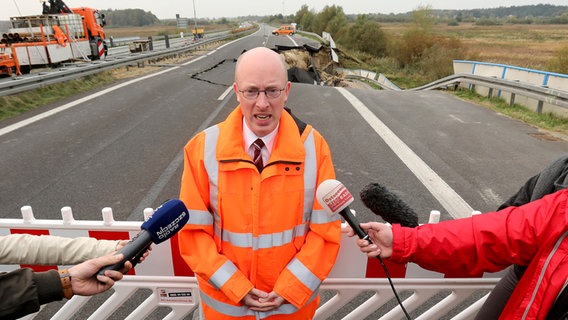 Infrastrukturminister Christian Pegel (SPD) steht am abgesackten Abschnitt der A 20 bei Tribsees und gibt ein Statement ab. © dpa Bildfunk Foto: Bernd Wüstneck