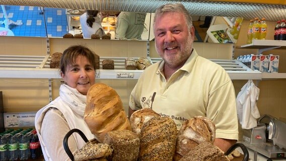 Bäckermeister Herrmann, Chef des Backhus Grabow, präsentiert in seinem Laden zusammen mit einer Kollegin einen Korb voller Brote. © NDR Foto: Franziska Drewes