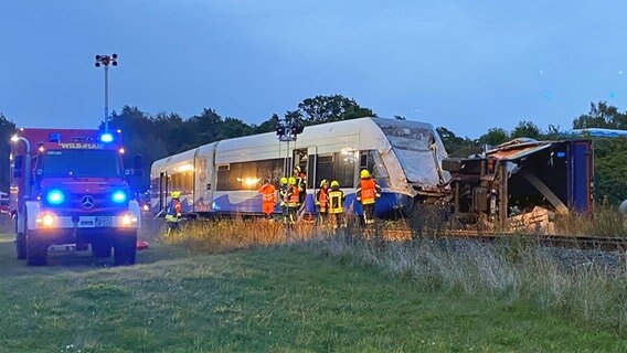 Vor einem entgleisten Regionalzug liegt ein umgekippter Lastwagen. Links im Bild ist ein Feuerwehrfahrzeug mit Blaulicht zu sehen, an dem Zug arbeiten acht Feuerwehrleute. © Tilo Wallrodt Foto: Tilo Wallrodt