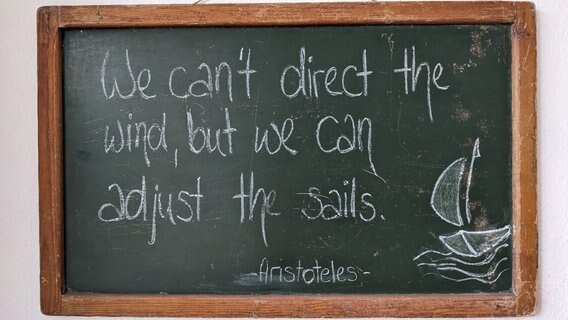 Ein Spruch des griechischen Philosophen Aristoteles auf einer Wandtafel des Seemannsclubs. "We can't direct the wind, but we can adjust the sails." Ein Spruch des griechischen Philosophen Aristoteles auf einer Wandtafel des Seemannsclubs. "We can't direct the wind, but we can adjust the sails." © NDR Foto: Katja Bülow