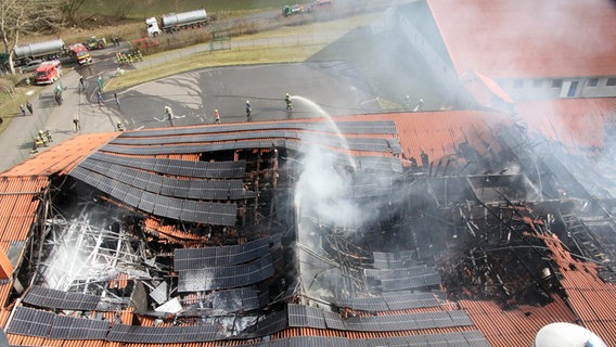 Kobrow: Mehrere Feuerwehrleute versuchen, den Brand in einer Schweinemastanlage unter Kontrolle zu bekommen. Das Dach des Gebäudes ist bereits eingestürzt. © Michael-Günther Bölsche Foto: Michael-Günther Bölsche