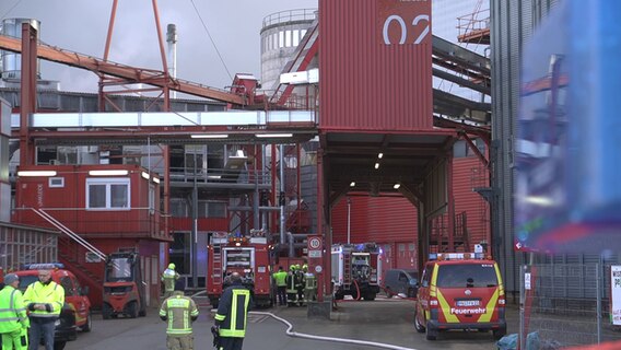 Feuerwehrleute und Einsatzfahrzeuge auf dem Gelände der Wismar Pellets GmbH. © NDR 