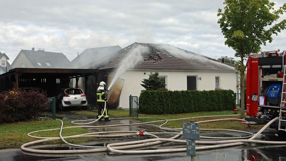Ein Feuerwehrmann löscht ein brennendes Haus in einer Wohnsiedlung. © Stefan Tretropp Foto: Stefan Tretropp