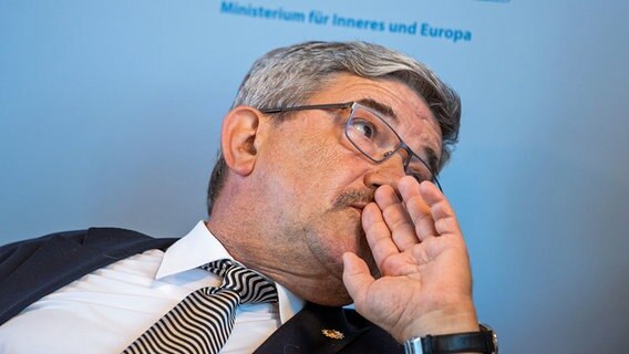 Innenminister Lorenz Caffier (CDU) sitzt bei einer Pressekonferenz auf einem Podium. © dpa picture alliance Foto: Jens Büttner