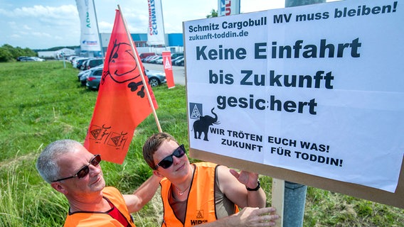 Mitglieder der Streikwache hängen in Toddin an der Zufahrt zur Fahrzeugbau-Firma Schmitz Cargobull ein Plakat auf. © dpa-Bildfunk Foto: Jens Büttner