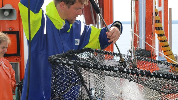 Ein Mann reinigt auf dem Forschungsschiff "Clupea" eine Fischfalle mit einem Hochdruckreiniger.  Foto: Claudio Campagna