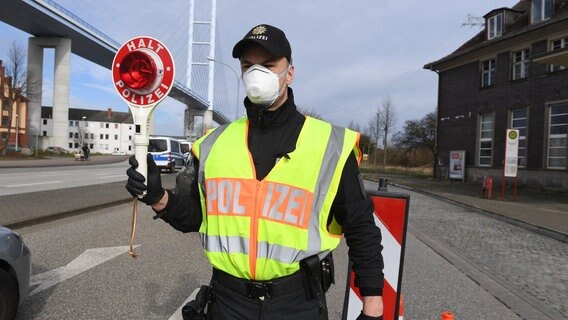 Ein Polizist mit Schutzmaske kontrolliert die Zufahrt zur Ostseeinsel © dpa Foto: Stefan Sauer