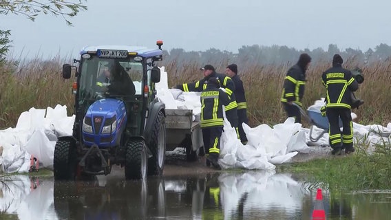 Durch das Hochwasser ist in Wieck am Darß ein Deich gebrochen. Feuerwehrleute platzieren Sandsäcke. © NDR Foto: NDR Screenshots