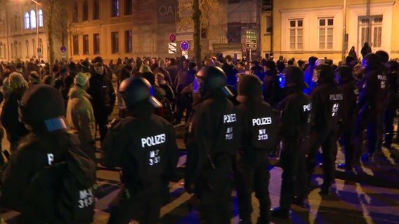 Eine Reihe behelmter Polizisten steht in Rostock vor einer Menschenmenge. © TeleNewsNetwork Foto: TeleNewsNetwork