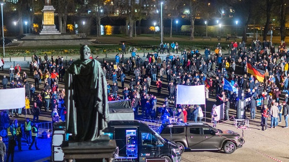 Demonstranten sammeln sich in der abendlichen Dunkelheit zu einer Demo auf dem Alten Garten in Schwerin. © dpa Foto: Jens Büttner