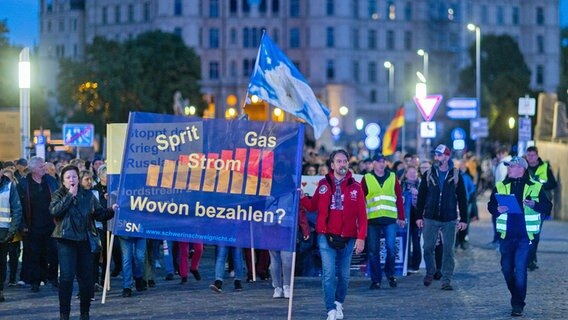 Demonstranten ziehen bei einer Protestaktion gegen die Energiepolitik des Bundes und gegen die Sanktionen gegen Russland vor dem Schweriner Schloss durch die Innenstadt. © dpa Foto: Jens Büttner