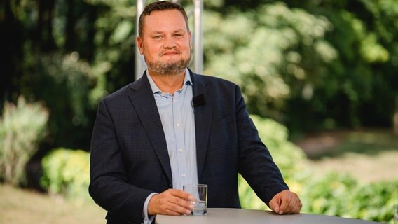 Der FDP-Politiker René Domke steht an einem Tisch während eines Interviews. © NDR Foto: Katharina Kleinke