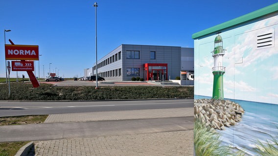 Blick auf das Norma-Logistikzentrum in Dummerstorf. Vorne rechts im Bild ist ein Trafohäuschen zu sehen, auf das ein Leuchtturm gemalt ist. © IMAGO / BildFunkMV Foto: IMAGO / BildFunkMV