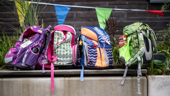 Vier Schulranzen stehen bei einer Einschulung nebeneinander. © dpa Foto: Bernd Thissen