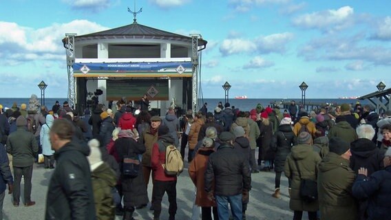 Many people crowd in front of the stage on the Binz Kurplatz.  The Baltic Sea can be seen in the background.  © NDr Photo: NDR