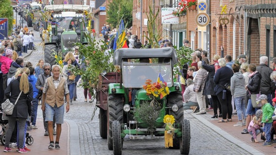 Ein grüner Traktor fährt durch eine von Zuschauern gesäumte Stadt. Dahinter folgen weitere Traktoren. © Landkreis Nordwestmecklenburg Foto: ARCHIV