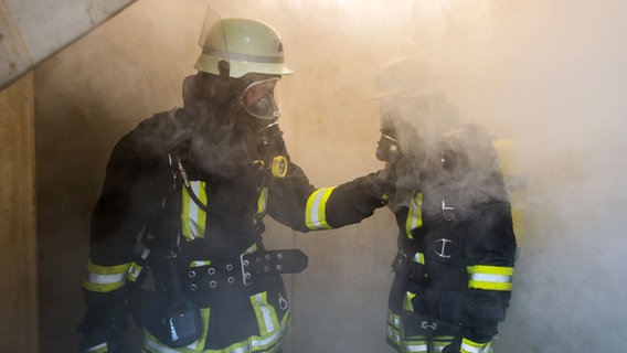 Zwei Feuerwehrleute mit Atemschutzmasken stehen in einem verrauchten Gebäude. © Fotolia Benjamin Nolte Foto: Benjamin Nolte