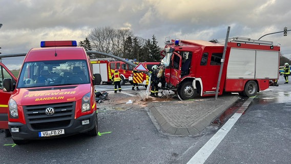 Nach einem Unfall auf einer Straßenkreuzung stehen mehrere Feuerwehrautos auf der Straße, eines davon mit erheblichen Schäden. © Ch. Niemann Foto: Ch. Niemann
