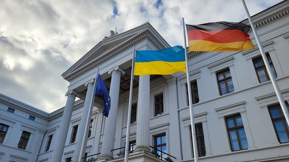 Vor der Fassade der Schweriner Staatskanzlei flattern die deutsche und die ukrainische Fahne im Wind. © NDR 