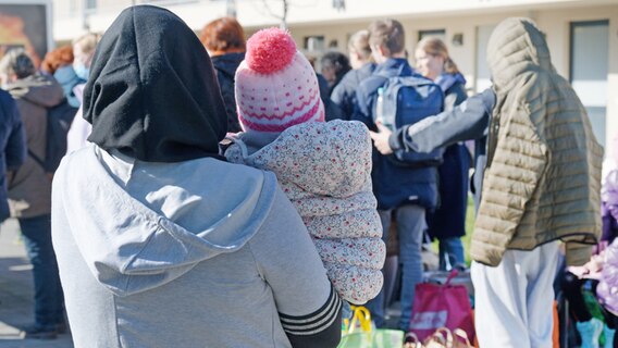 Geflüchtete aus der Ukraine stehen mit ihrem Gepäck vor den Gebäuden eines Flüchtlingsheims (Symbolbild). © dpa Foto: Henning Kaiser