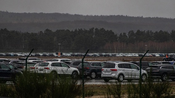 Tausende Autos stehen hinter einem Stacheldrahtzaun auf dem Vorfeld und der Rollbahn des Flughafens. © NDR Foto: Christoph Loose