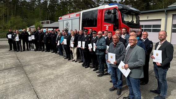 Viele Menschen stehen vor einem Feuerwehrauto. Sie gucken in die Kamera und zeigen Urkunden in die Kamera. © Landkreis Nordwestmecklenburg Foto: Tore Degenkolbe