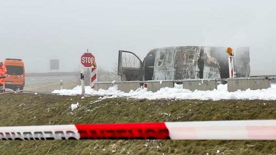 Ein ausgebrannter Geldtransporter steht an einer Autobahn, im Vordergrund rotes Flatterband. © NDR Foto: Felix Gadewolz