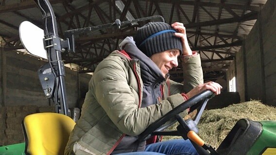 Svenja Winter sitzt auf einem Traktor in einer großen Halle auf dem Gut Bisdorf © Svenja Winter / Charlotte Linder Foto: Svenja Winter / Charlotte Linder